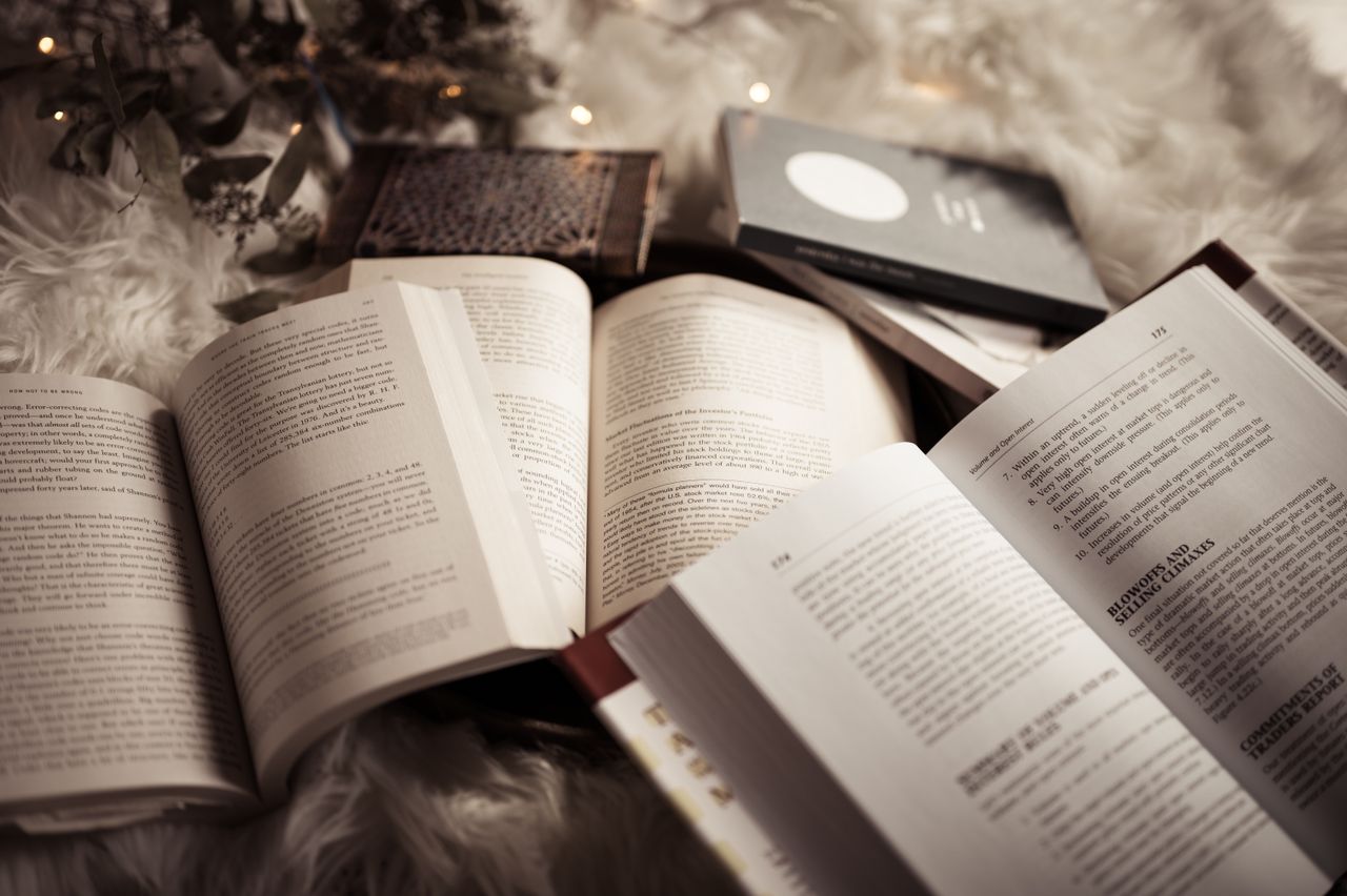 Open books placed on a soft, fluffy rug, surrounded by warm, ambient lighting for a cozy reading atmosphere.
